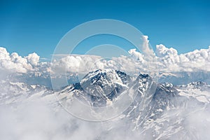 Dark blue sky with clouds on the rocky peaks of the mountains covered with glaciers and snow