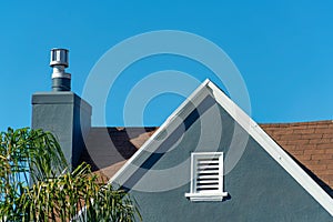Dark blue stucco house facade or exterior with white accent paint on roof edge and visible chimney and vent on house