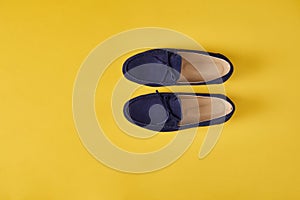 Dark blue suede man`s moccasins shoes over yellow background