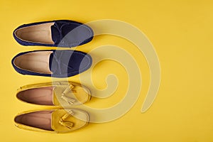 Dark blue suede man`s and yellow woman`s moccasins shoes over yellow background
