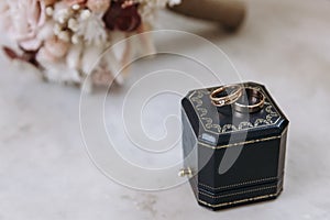 Dark blue wedding box with wedding rings inside on white marble stone. Wedding bouquet of dried flowers. Holiday concept