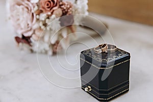 Dark blue wedding box with wedding rings inside on white marble stone. Wedding bouquet of dried flowers. Holiday concept
