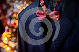 Dark blue wedding suit and wine-colored bow-tie on blurred background. Butterfly necktie on the man& x27;s costume. Close