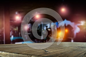 Dark blurred background of bar restaurant and brown wooden table top with space for advertising product.