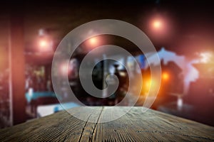 Dark blurred background of bar restaurant and brown wooden table top with space for advertising product.