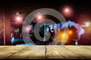 Dark blurred background of bar restaurant and brown wooden table top with space for advertising product.