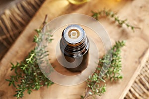 A dark bottle of aromatherapy essential oil with fresh thyme leaves