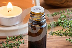 A dark bottle of thyme essential oil with fresh thyme twigs