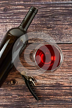 Dark bottle of wine and glasses on wooden background. Top view with copy space