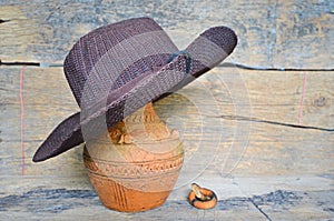 Dark brown hat on old baked clay jar