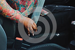 Dark brown skin African woman hand buckling safety belt in the car for automobile accident safety concept