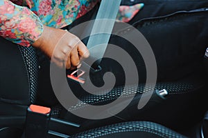 Dark brown skin African woman hand buckling safety belt in the car for automobile accident safety concept