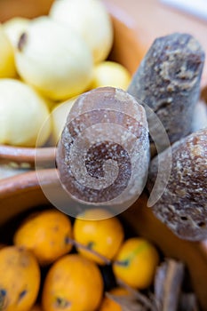 Dark brown sugar canes above clay bowls of fruit