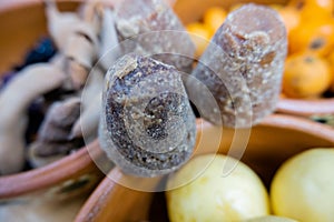 Dark brown sugar canes between clay bowls of fruit