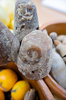 Dark brown sugar canes between clay bowls of fruit