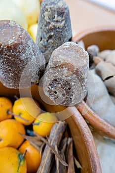 Dark brown sugar canes between clay bowls of fruit