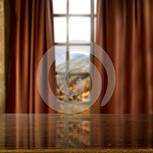 A brown table with blurred mountains and blue cloudy sky background behind the window.