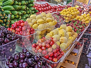 Dark cherries, cherries, apricots, strawberries and vegetables laid out on the counter of the farmers ` market