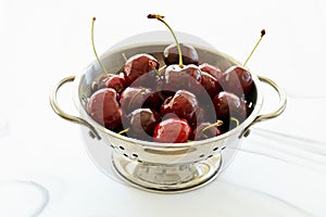 Dark cherries in rustic colander