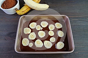 Dark Chocolate Banana Cake Batter in Cake Pan with Baking Ingredients on Wooden Table