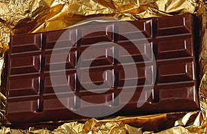 Dark chocolate bar on gold foil