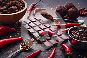 Dark chocolate bar, red hot chilli pepper cayenne, dry hot chili spices, cocoa beans nibs powder, food tasty design on black