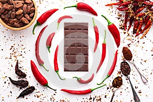 Dark chocolate bar, red hot chilli pepper cayenne, dry hot chili spices, cocoa beans nibs powder, food tasty design on black