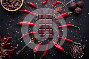 Dark chocolate bar, red hot chilli pepper cayenne, dry hot chili spices, cocoa beans nibs powder, food tasty design on black