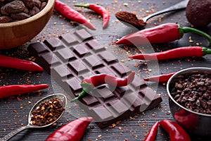 Dark chocolate bar, red hot chilli pepper cayenne, dry hot chili spices, cocoa beans nibs powder, food tasty design on black