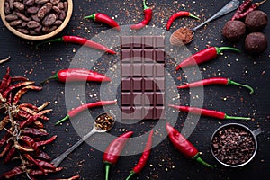 Dark chocolate bar, red hot chilli pepper cayenne, dry hot chili spices, cocoa beans nibs powder, food tasty design on black