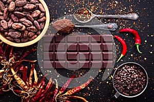 Dark chocolate bar, red hot chilli pepper cayenne, dry hot chili spices, cocoa beans nibs powder, food tasty design on black