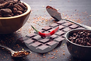 Dark chocolate bar, red hot chilli pepper cayenne, dry hot chili spices, cocoa beans nibs powder, food tasty design on black