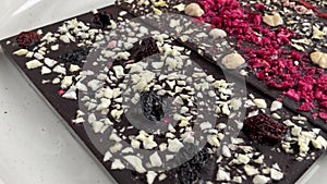 Dark chocolate bars with nuts and berries rotating on the plate video