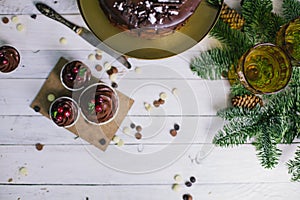 Dark chocolate cake with cookies and cupcakes berries on white wooden background