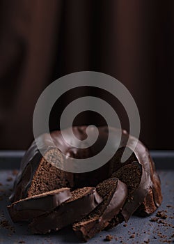 Dark chocolate cake covered with icing covered on a dark background. Selective focus.