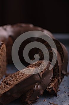 Dark chocolate cake covered with icing covered on a dark background. Selective focus.