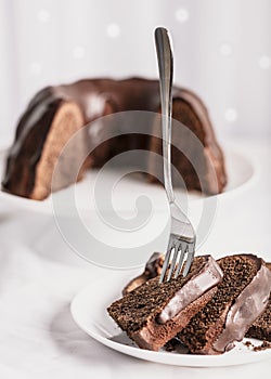 Dark chocolate cake covered with icing on a white stand. Selective focus.
