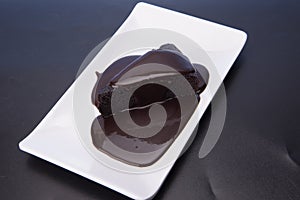 Dark chocolate with chocolate pouring isolated over dark reflective surface