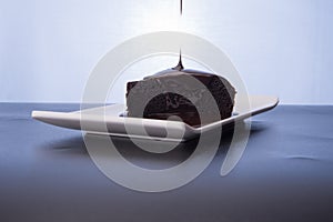 Dark chocolate with chocolate pouring isolated over dark reflective surface