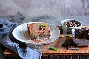 Dark chocolate dessert topped with coffee cream and sprinkled with cocoa powder