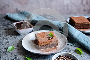 Dark chocolate dessert topped with coffee cream and sprinkled with cocoa powder