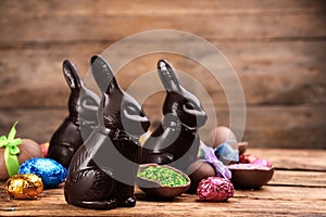 Dark chocolate Easter bunnies and eggs on wooden table. Space for text