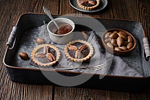 Dark chocolate ganache tarts topped with pecans, dusted with powdered sugar