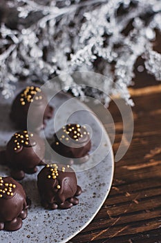 Dark chocolate handmade candy balls on handmade plate on dark wooden background with the cup of tea in a white cup