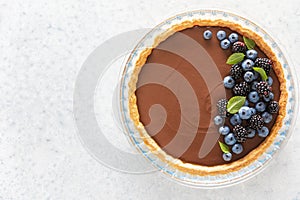 Dark chocolate mousse tart decorated with fresh blueberries and the mint, view from above