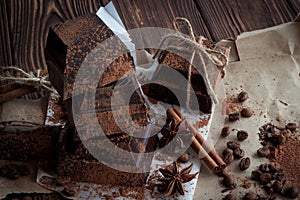 Dark chocolate on paper on wooden table with coffee bean, cocoa
