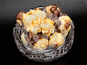 Dark chocolate sea salt caramel popcorn in mini crystal bowl on black background