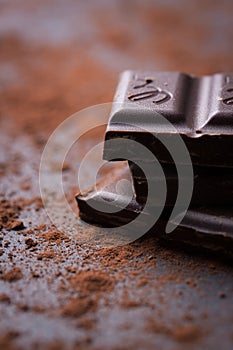 Dark chocolate stack with cocoa powder on a stone background