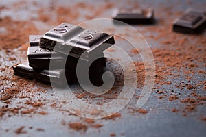 Dark chocolate stack with cocoa powder on a stone background with copy space