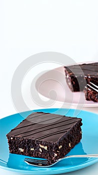 Dark chocolate vegan brownie cake with nuts blue and pink plate white background.